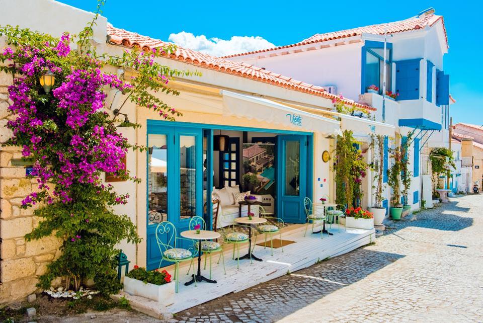 Alacati's beautiful blue-painted doors and windows on a street lined with Bougainvillea flowers.